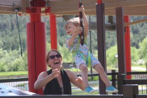 Toddler on a mini zipline with a parent helping