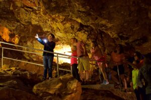 Rushmore Cave Guide points out an amazing formation inside the cave to a family taking a cave tour.