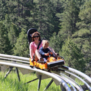 Mom and child riding together on the Rushmore Mountain Coaster
