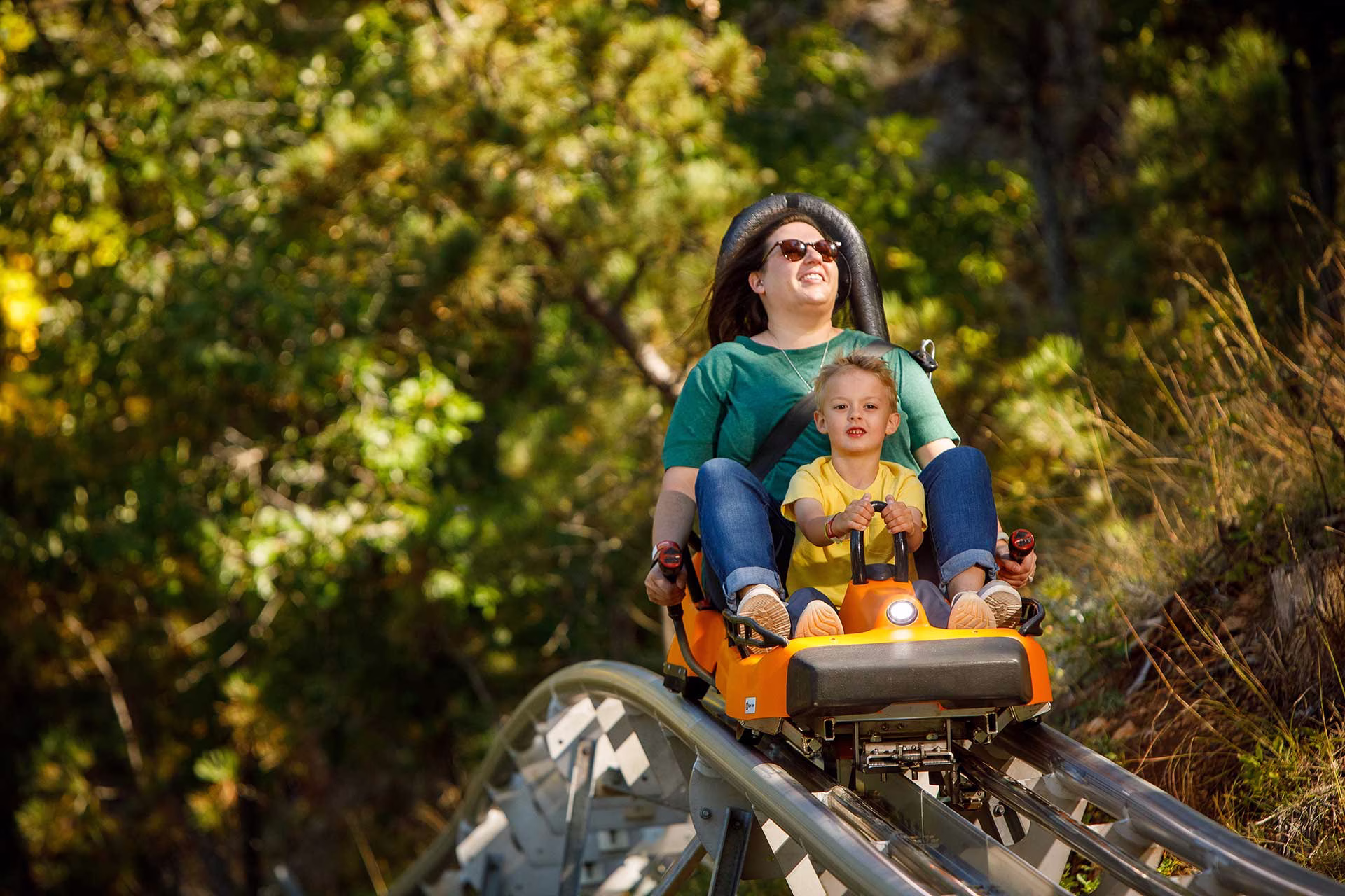 A mom and son ride the Rushmore Mountain Coaster at Rush Mountain Adventure Park in the Black Hills of South Dakota near Mount Rushmore